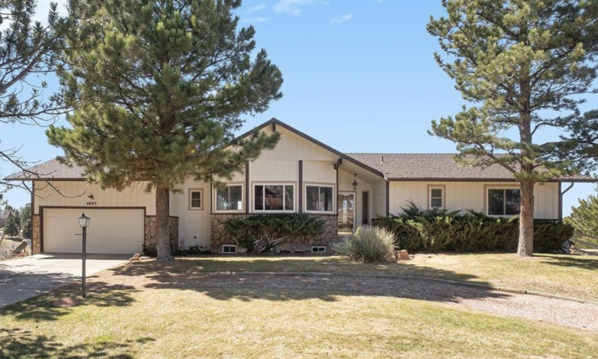 Original charming single-family home with sloped roof, surrounded by tall pine trees