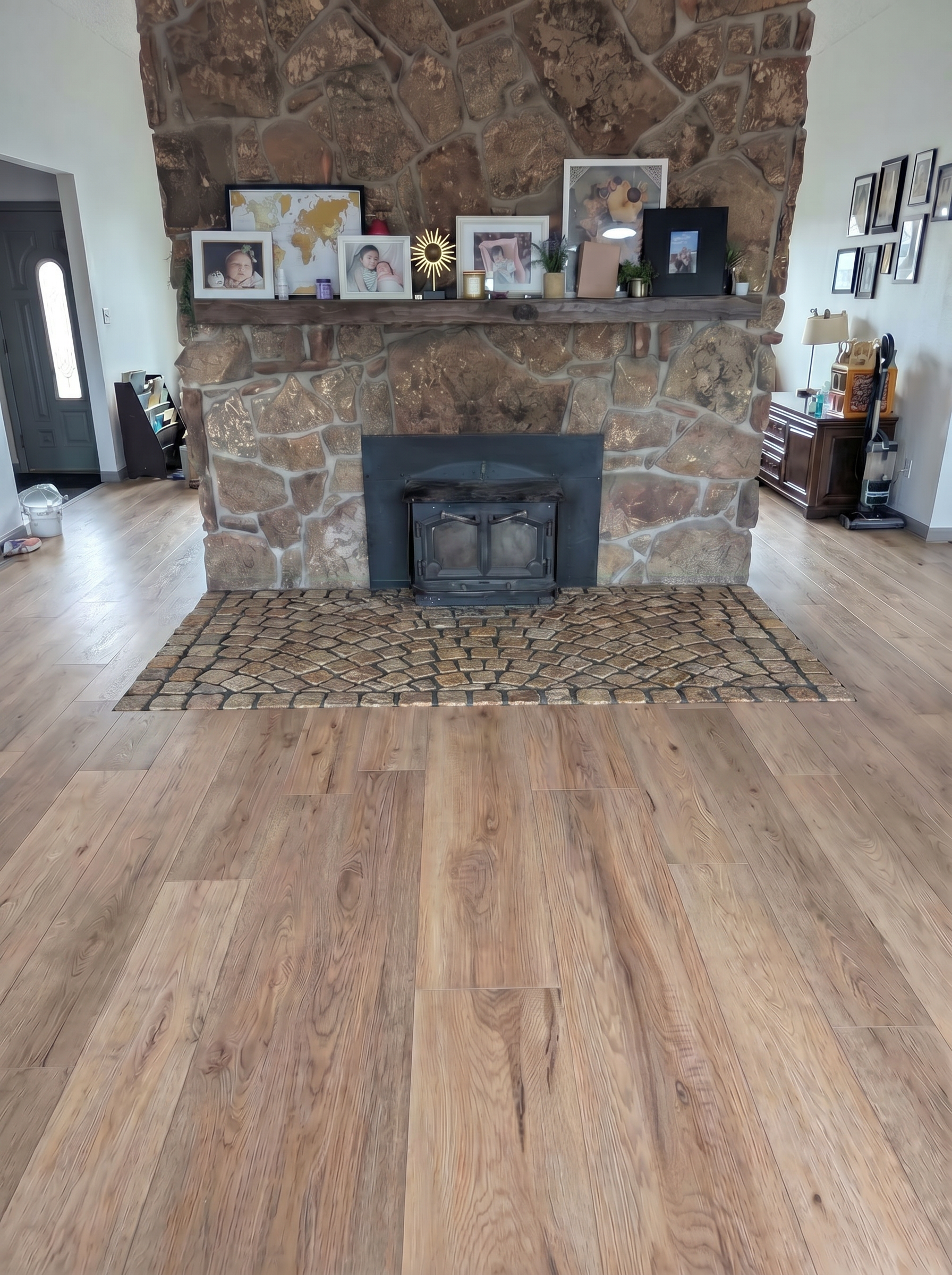 Spacious living room featuring a stone fireplace adorned with family photos and decor on the mantel
