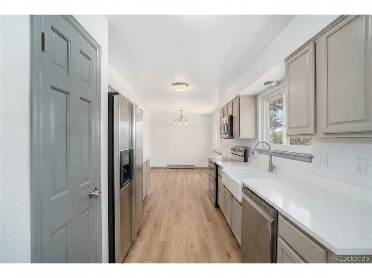 Modern kitchen interior with stainless steel appliances, light-colored cabinetry, and hardwood flooring