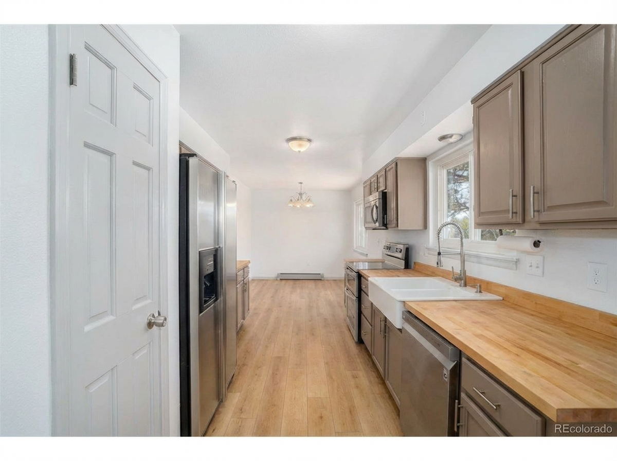 Spacious kitchen with stainless steel appliances, wooden countertops, and light-colored cabinetry