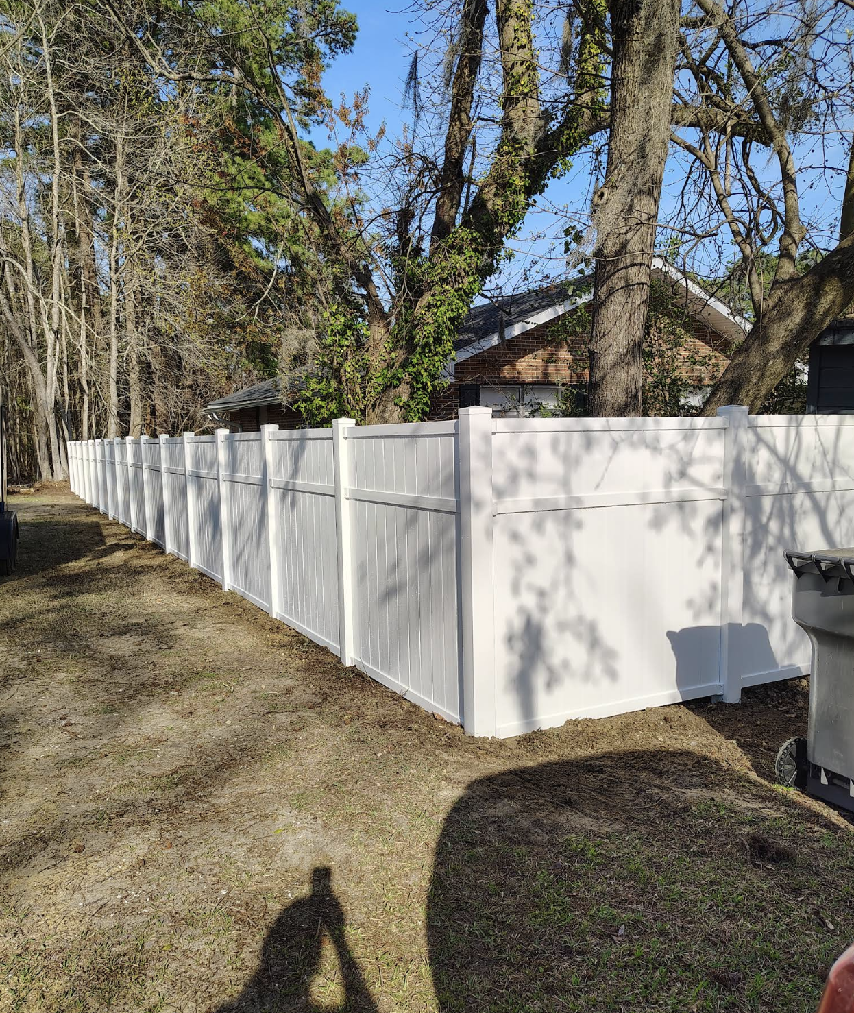 Long white vinyl privacy fence running along a well-maintained backyard