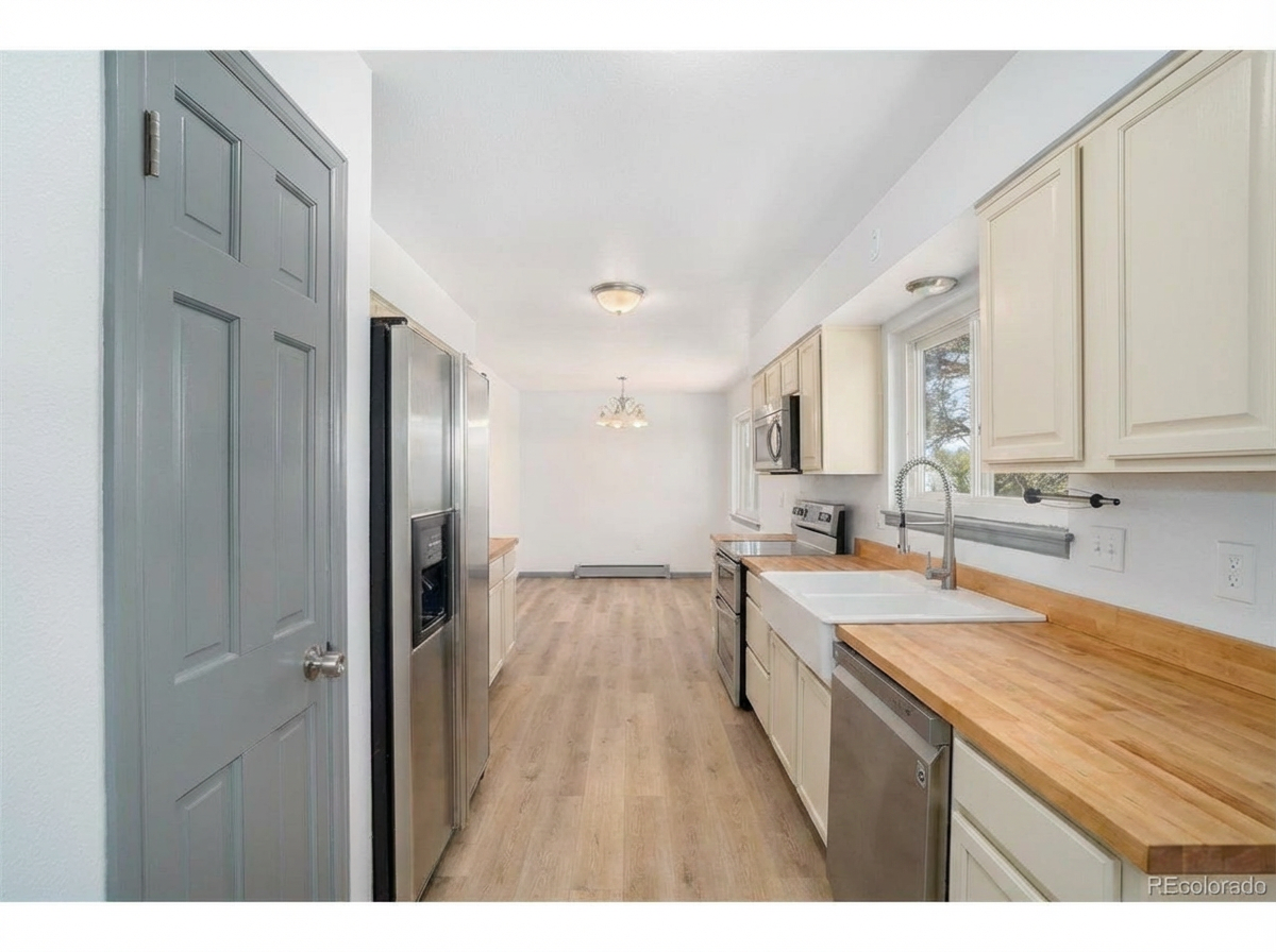 Modern kitchen with wooden countertops, stainless steel appliances, gray cabinetry, and bright dining area