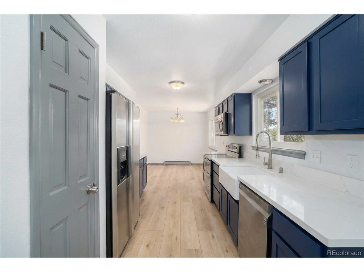 Modern kitchen interior with dark blue cabinets, stainless steel appliances, and white countertops