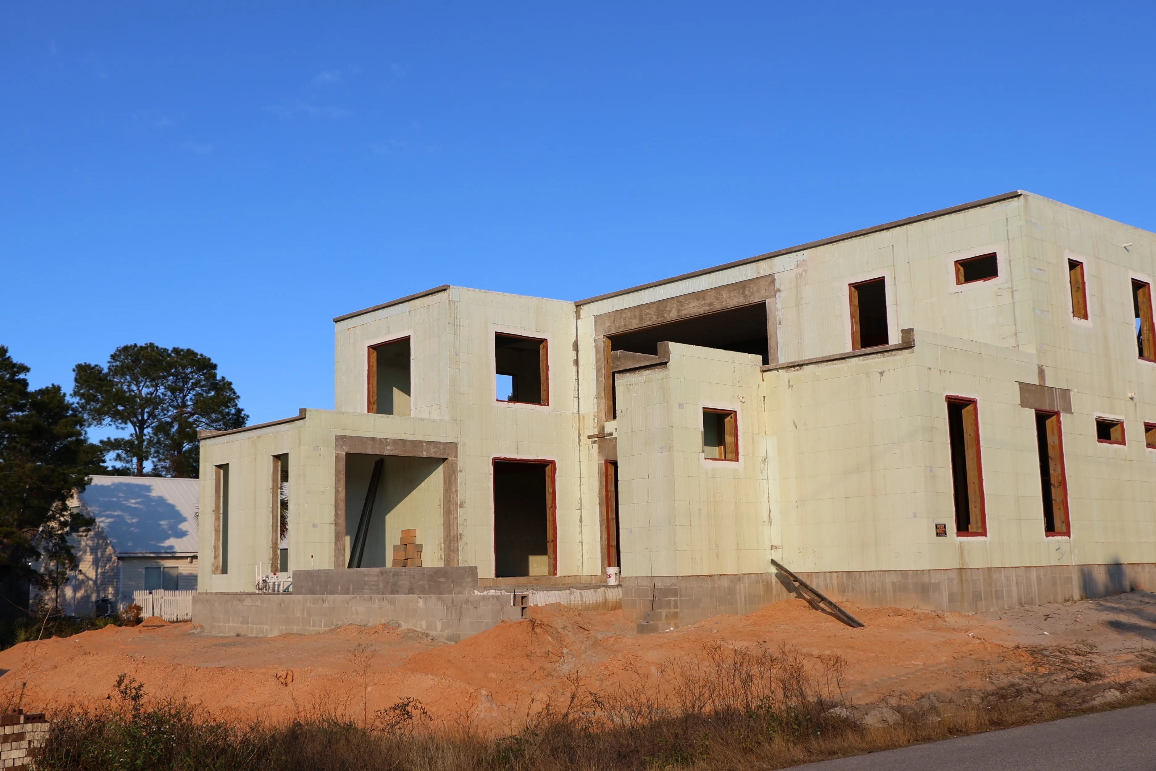 A two-storey JAT Specialties house under construction, its walls built from pale-green insulated concrete forms with window and door openings framed out.