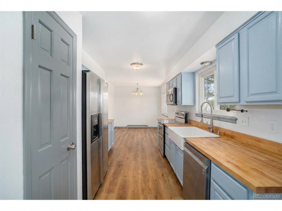 Spacious kitchen with light blue cabinets, stainless steel appliances, wooden countertops, and dining area