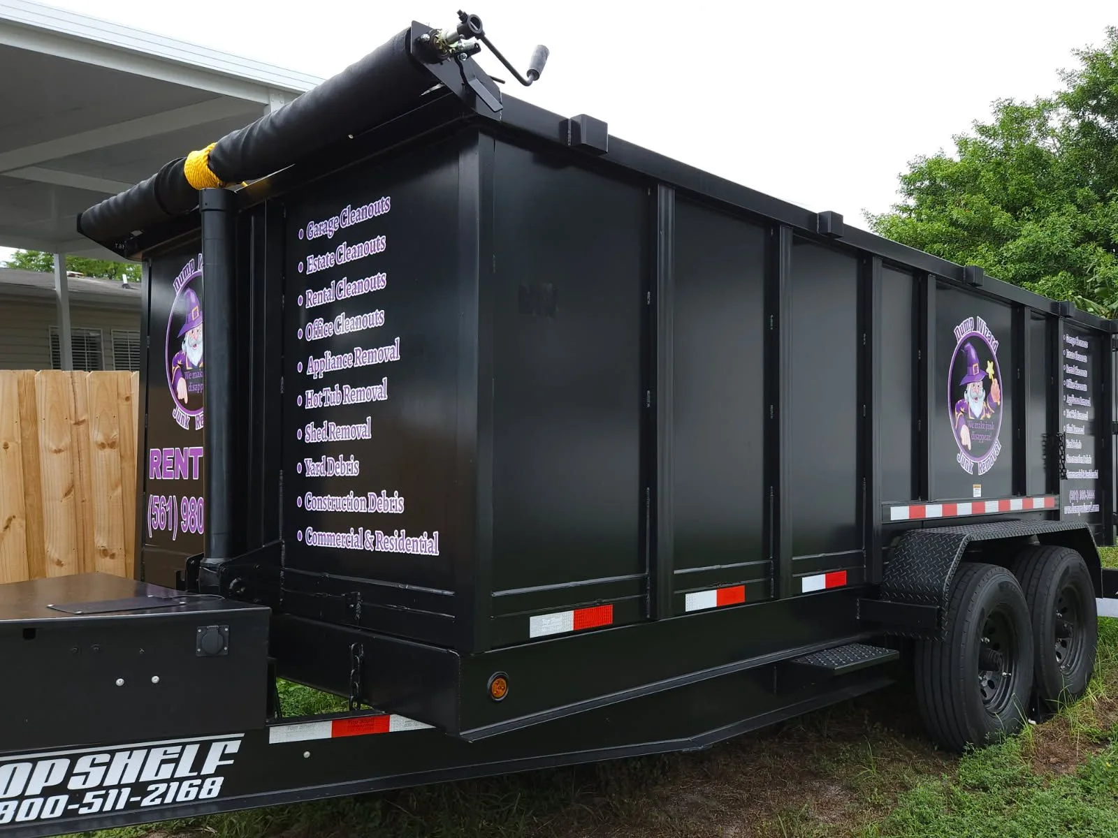 Side of the Dump Wizard trailer listing junk removal and dumpster rental services
