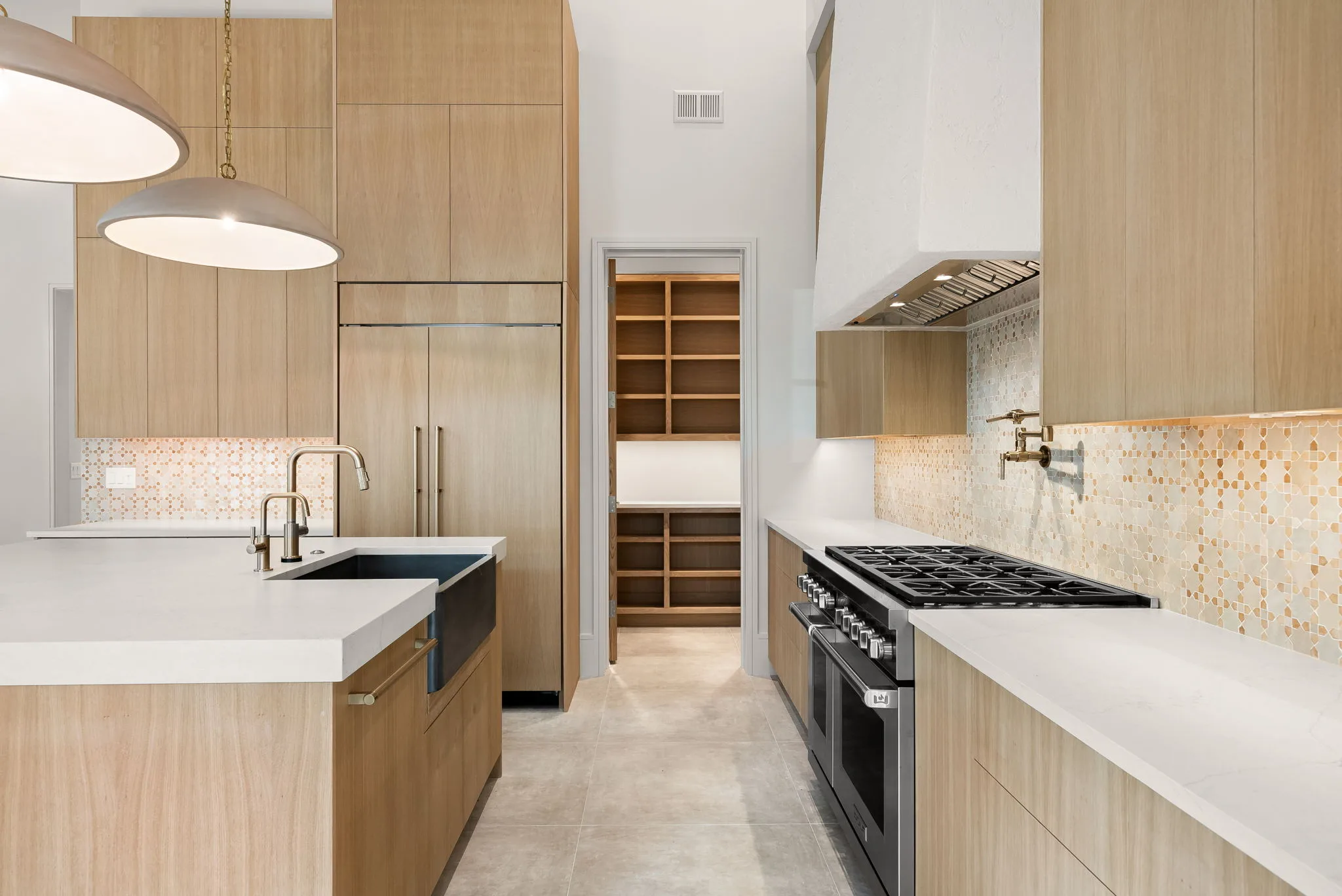 A kitchen with wood cabinets, a large island with white counters and a gas range.