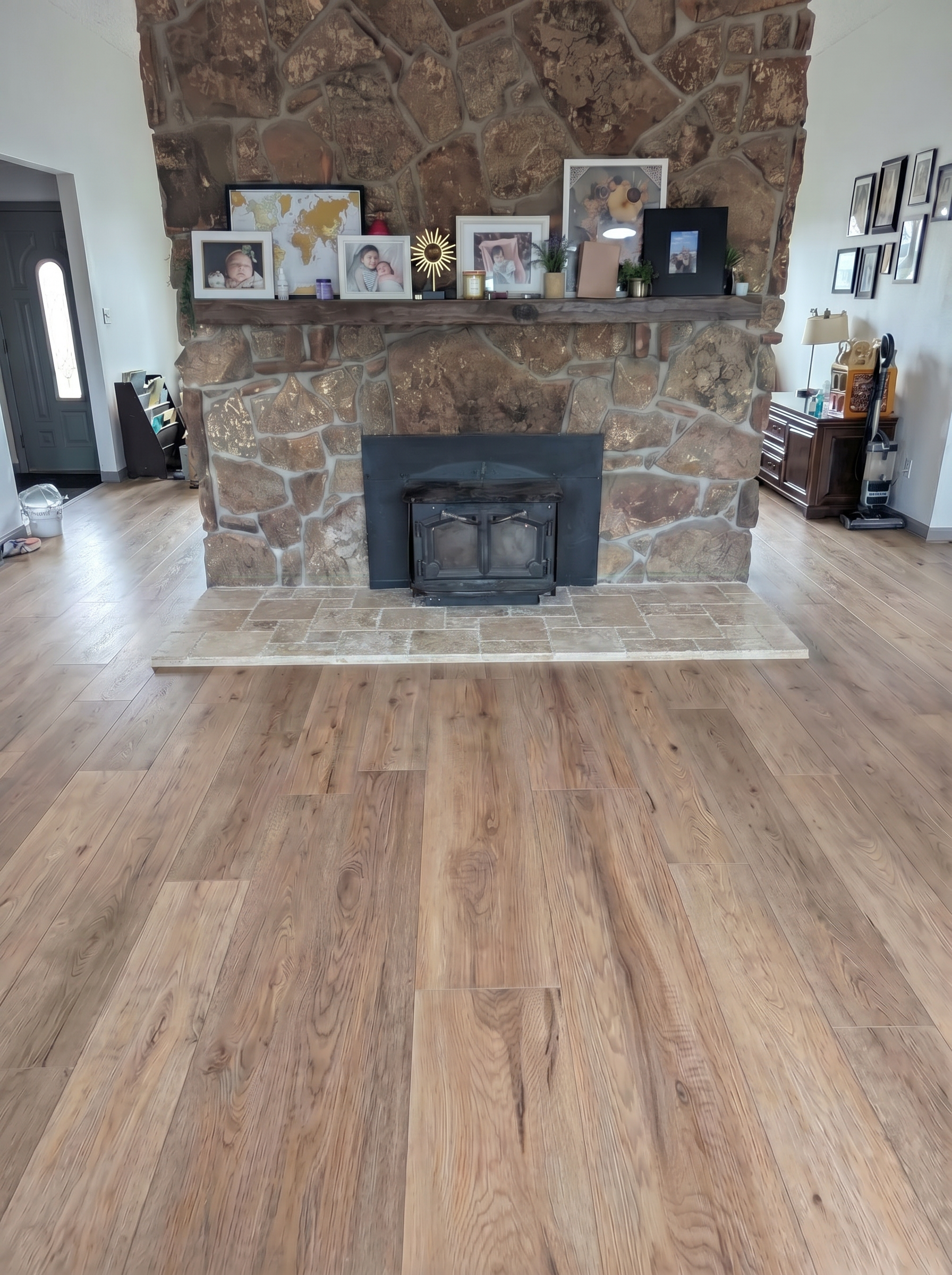 Spacious living room featuring a rustic stone fireplace with a black metal insert