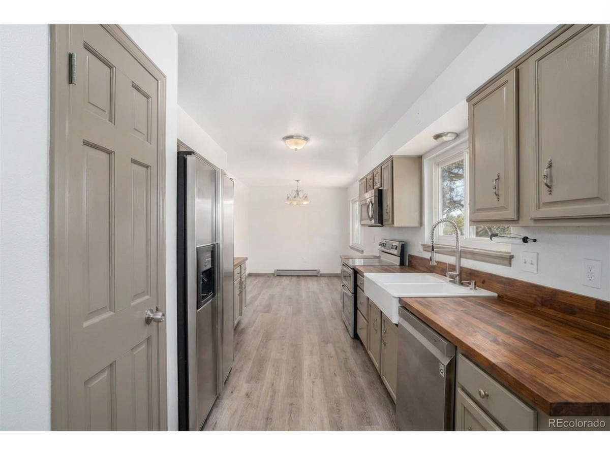 Spacious modern kitchen with stainless steel appliances, light cabinetry, farmhouse sink, and wooden countertops