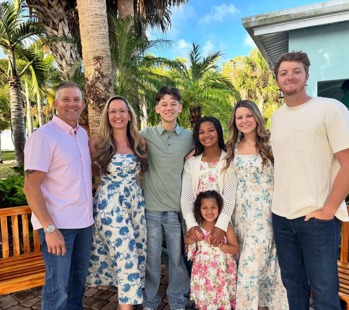 A family standing outdoors in front of tropical palm trees on the Treasure Coast