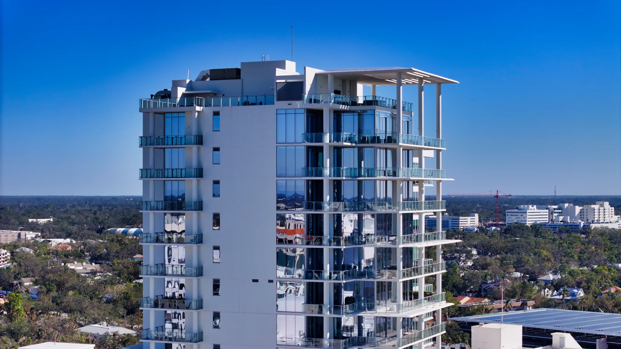 Aerial of The Epoch, a glass-and-white residential tower, against a clear blue sky.