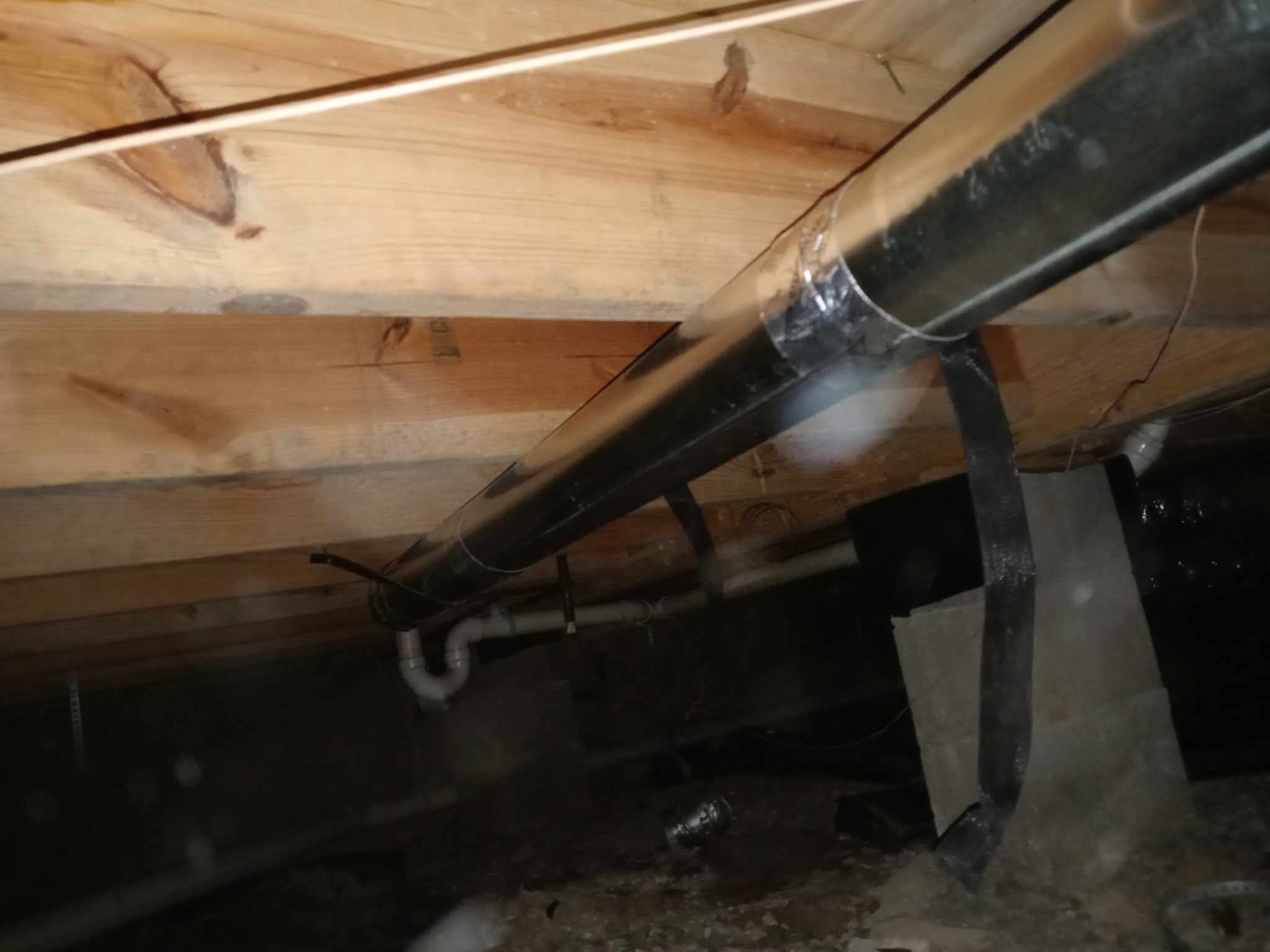 Underfloor space with wooden joists and pipes showing a plumbing and HVAC system