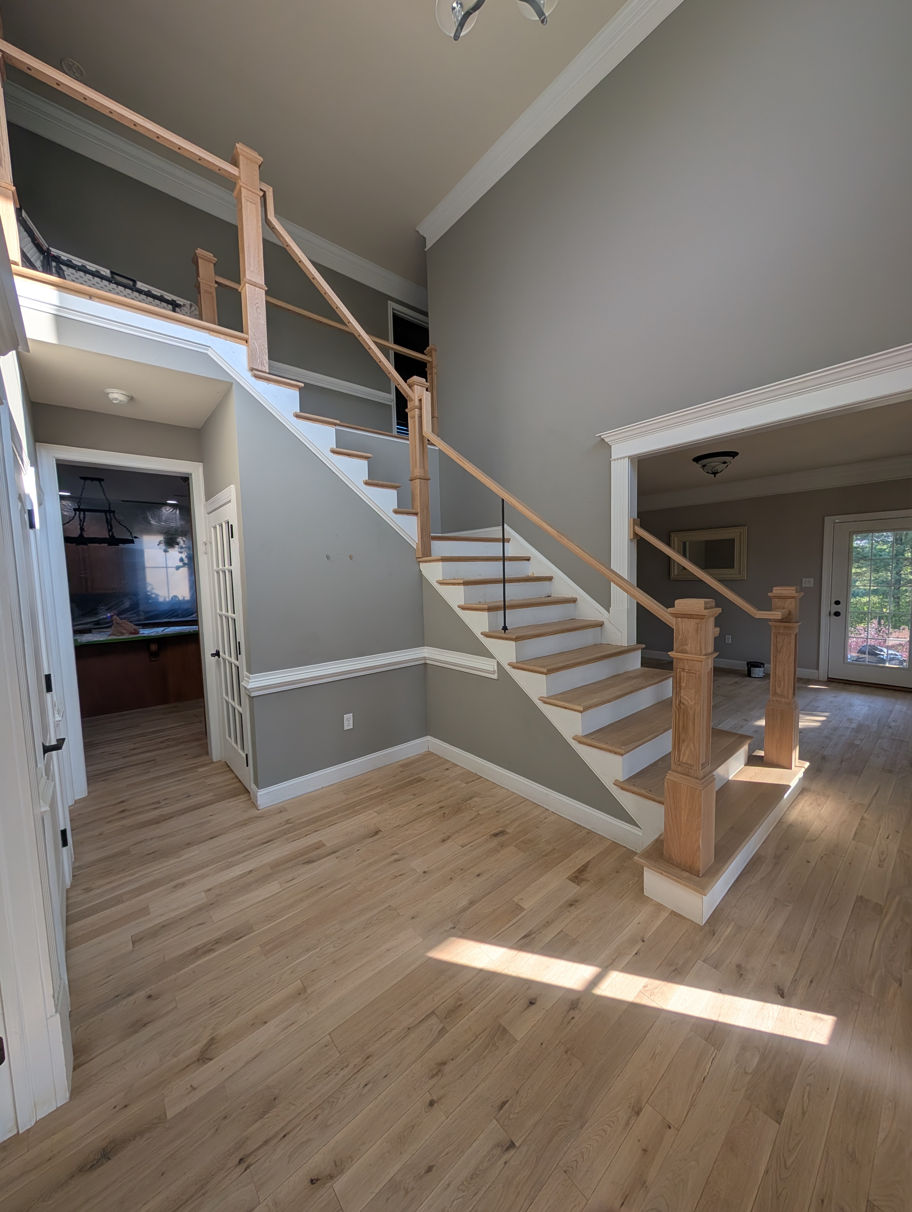 Elegant entryway with wooden staircase, polished banister, and warm hardwood flooring