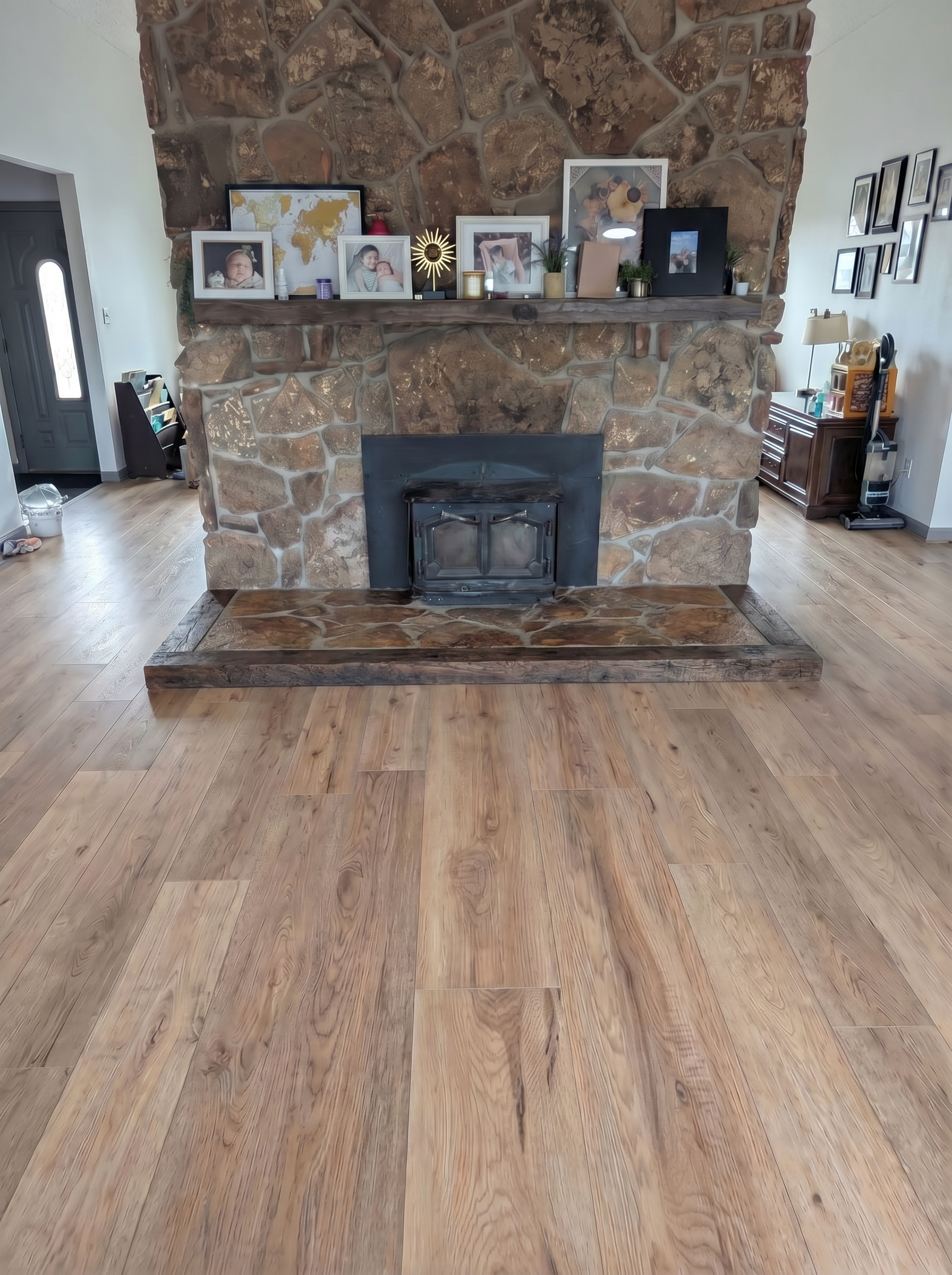 Stone-faced fireplace with a wooden mantel adorned with framed photos and decorative items