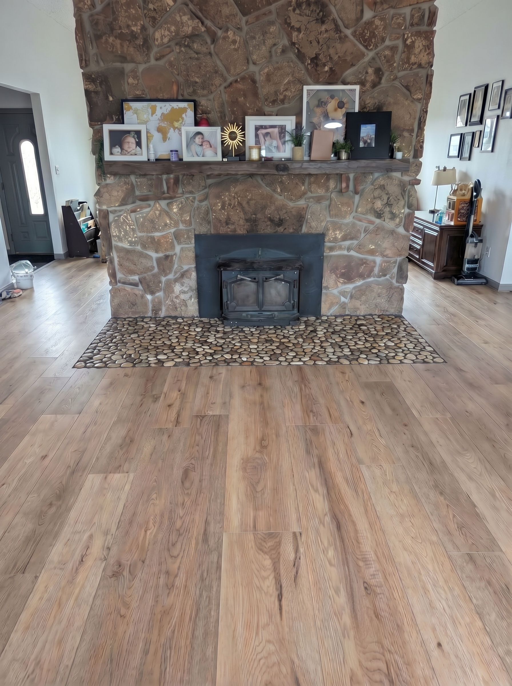 Spacious living room featuring a stone fireplace with framed photographs and decorative items on a wooden mantel