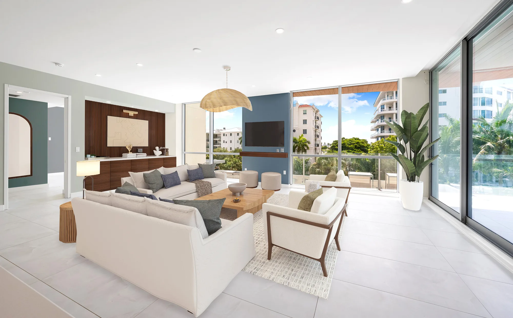 This image showcases a spacious modern living room featuring a neutral color palette with plush furniture and decorative accents. Large windows provide a scenic view of the outdoors, blending indoor and outdoor spaces.
