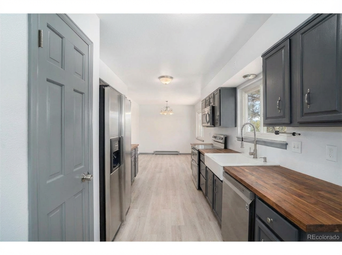 Spacious modern kitchen with dark gray cabinets, stainless steel appliances, and wooden countertops