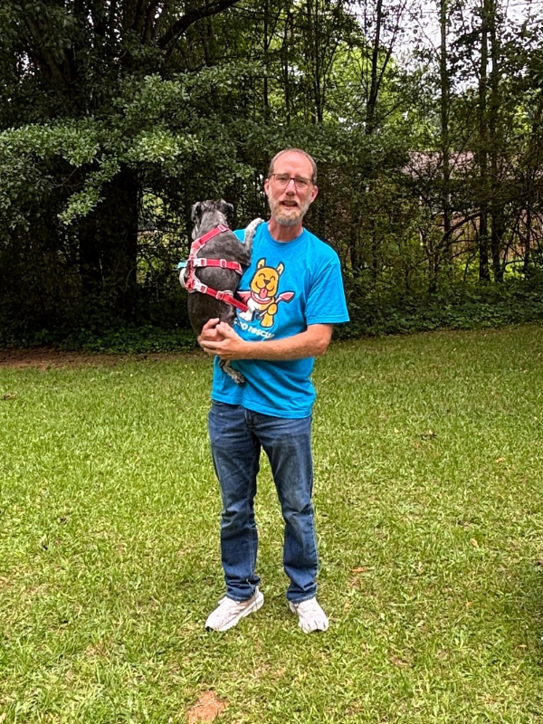Scoop Rescue owner holding a dog in a freshly cleaned yard
