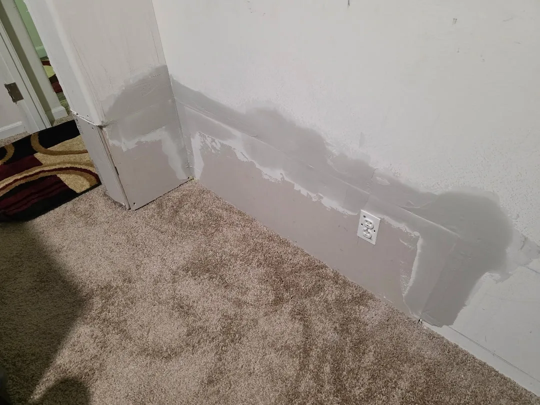 Wall repair in progress with joint compound over a patched section