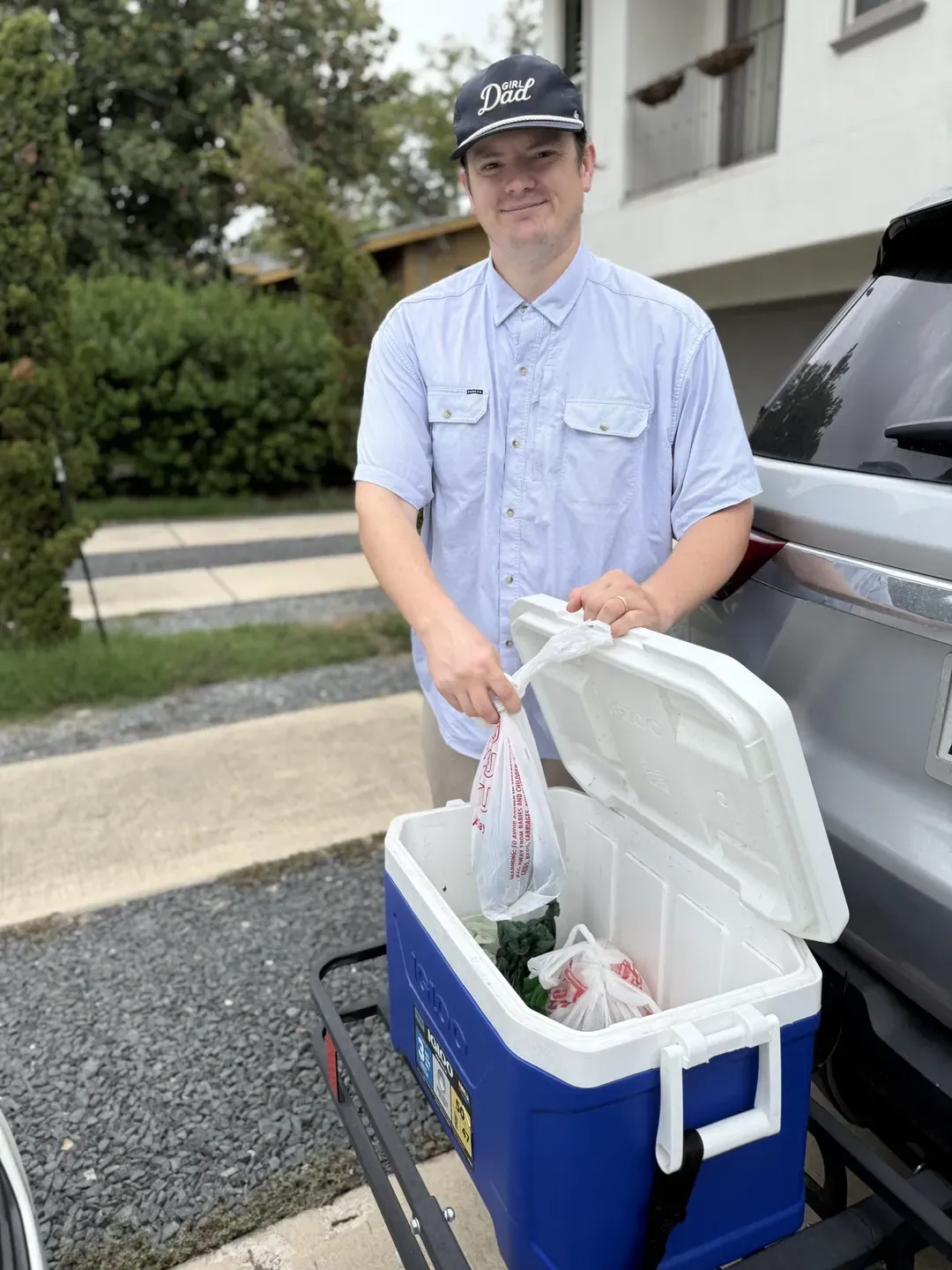 B.P. Foley placing a bag of collected waste into a blue cooler on a rack at the back of his SUV