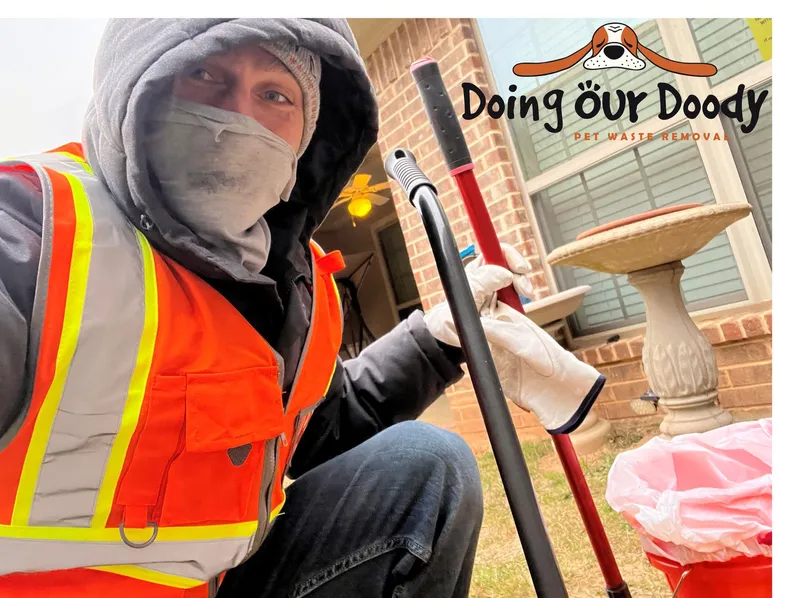 Pet waste removal worker crouching with tool and red bucket in a residential yard