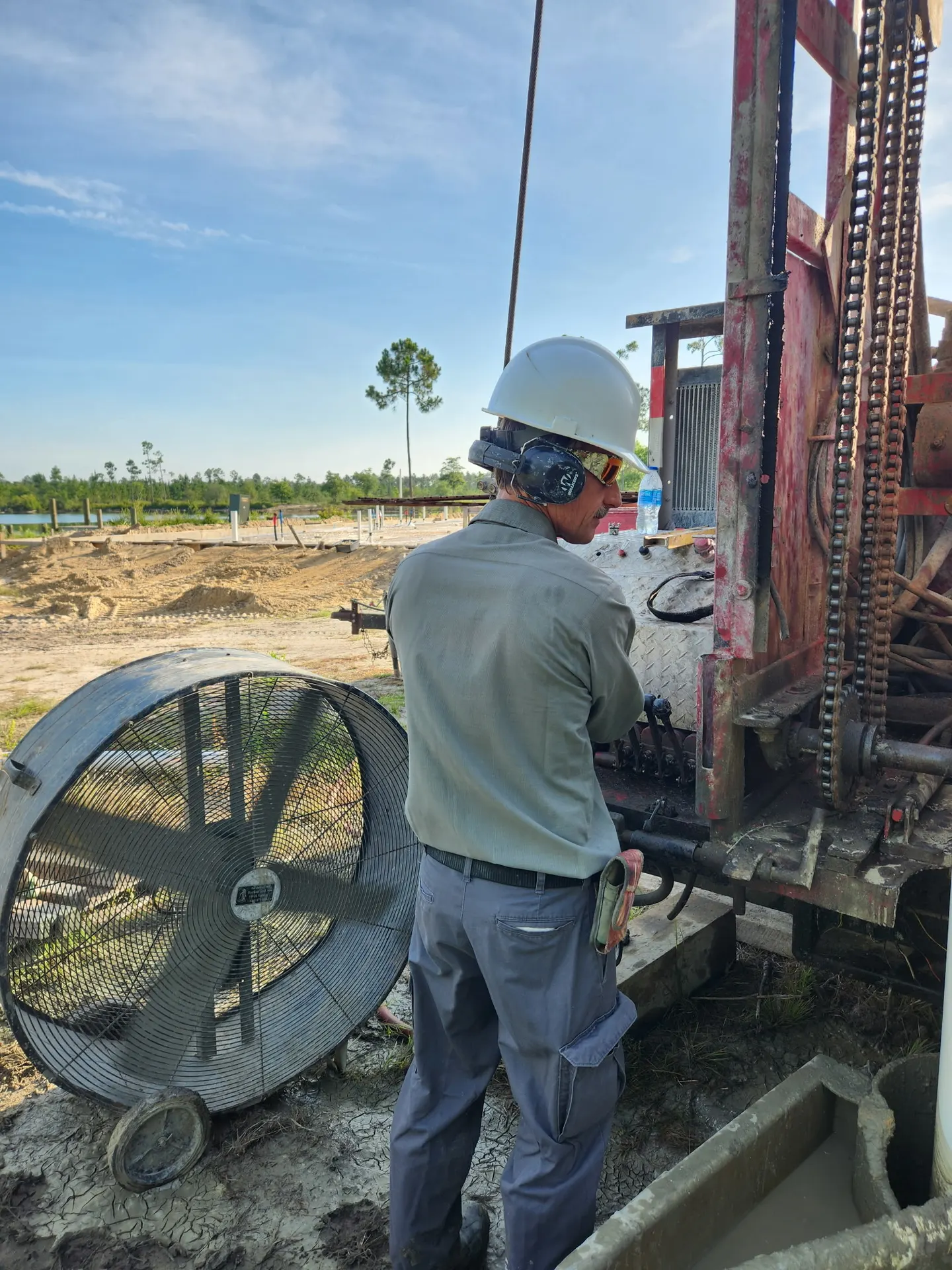 Driller in hard hat and ear protection on the rig controls