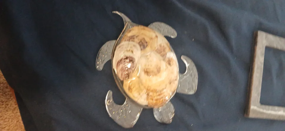 Turtle-shaped decoration with a patterned shell body and translucent flippers on dark blue fabric