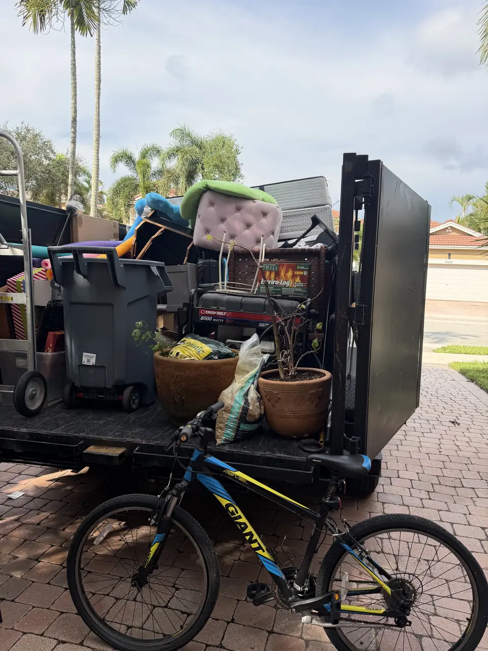 Dump Wizard trailer loaded with bins, planters, chairs, and household items at the Parkland job