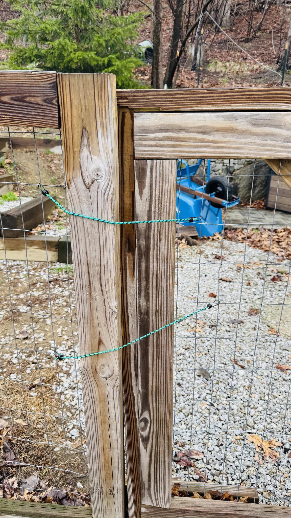 Close up of a wooden gate panel tied shut with green cord after a visit