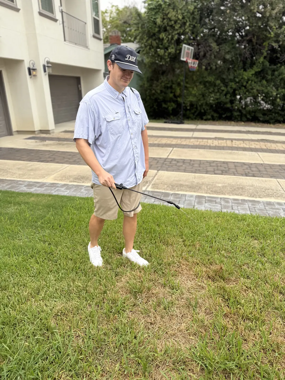 B.P. Foley holding a spray wand over a front lawn