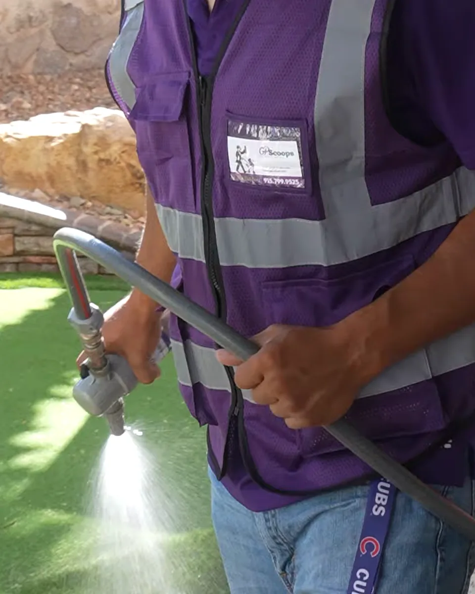 GP Scoops service provider spraying artificial turf with a hose nozzle