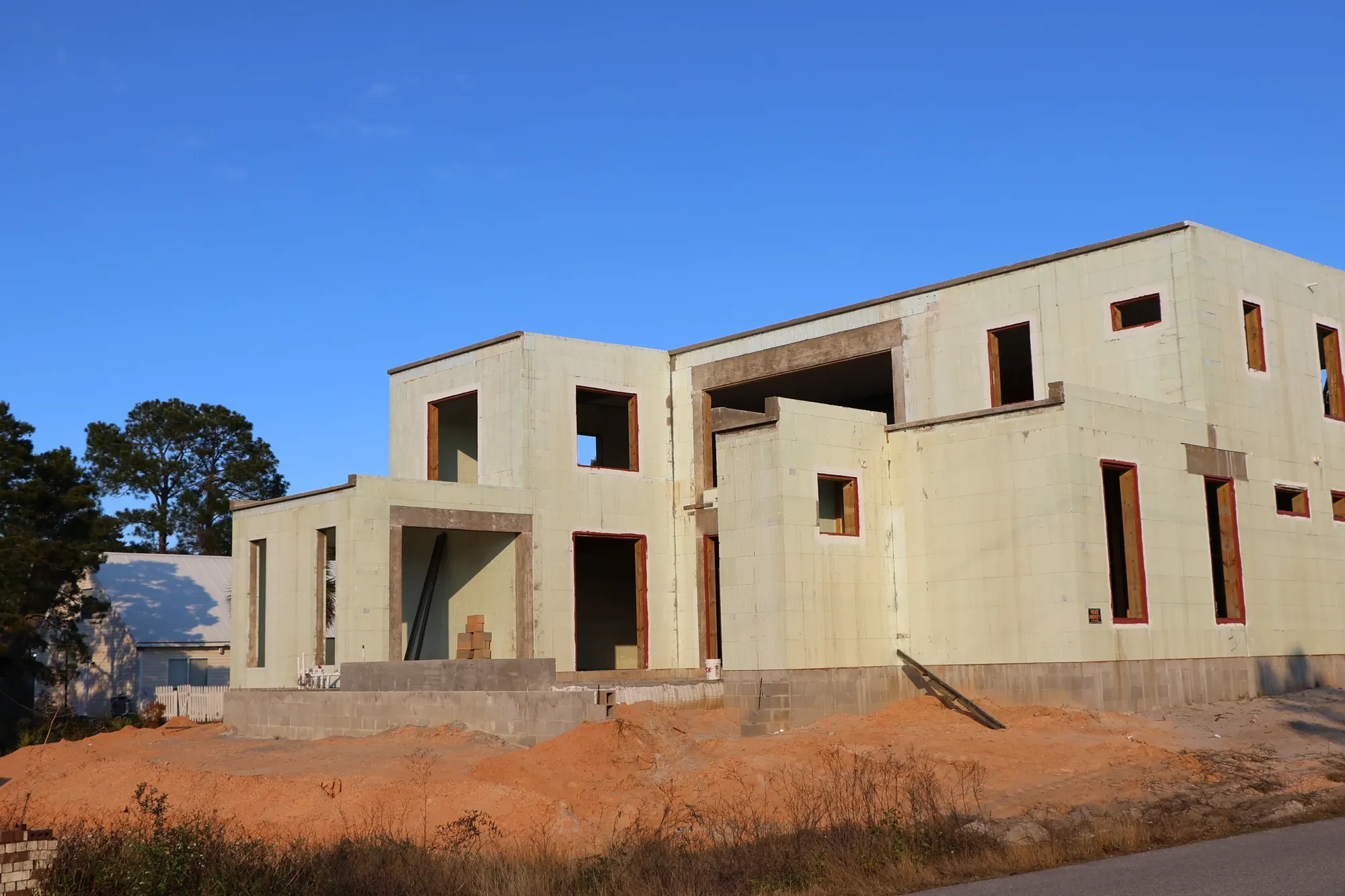 A two-storey JAT Specialties house under construction, its walls built from pale-green insulated concrete forms with window and door openings framed out.