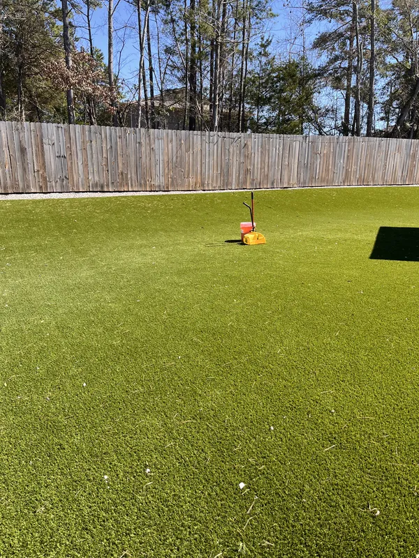 Vibrant green artificial turf lawn with maintenance tool on a sunny day