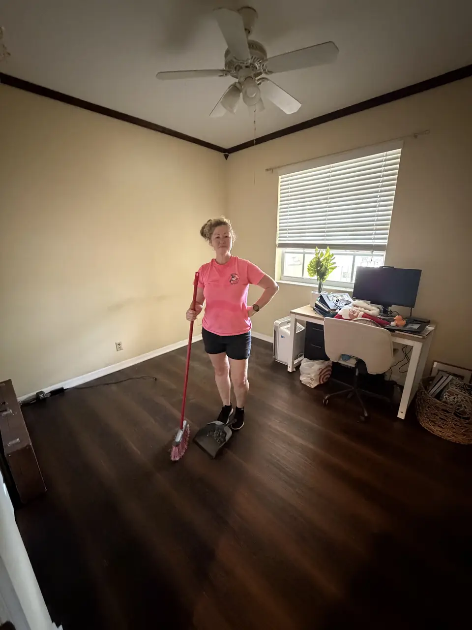 Dump Wizard crew member sweeping a cleared room with a broom and dustpan as the Parkland job wraps up