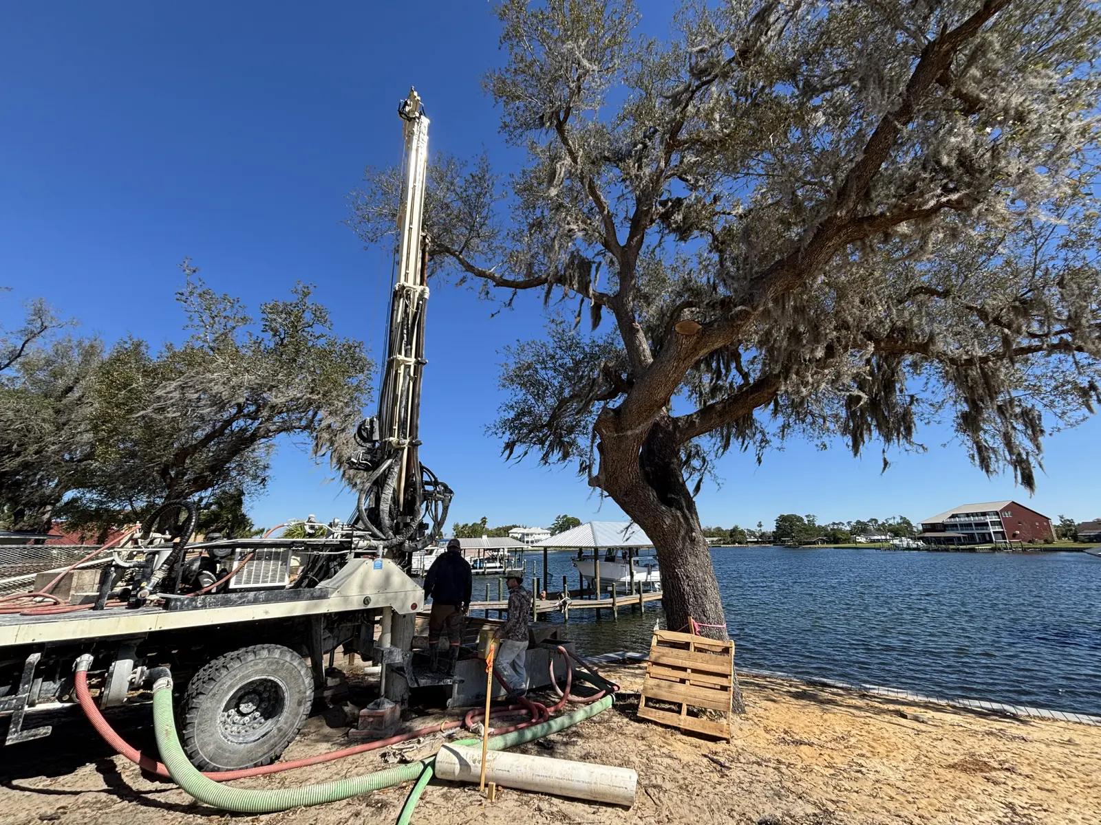 Drilling rig set up near the water with pipe staged on the shore