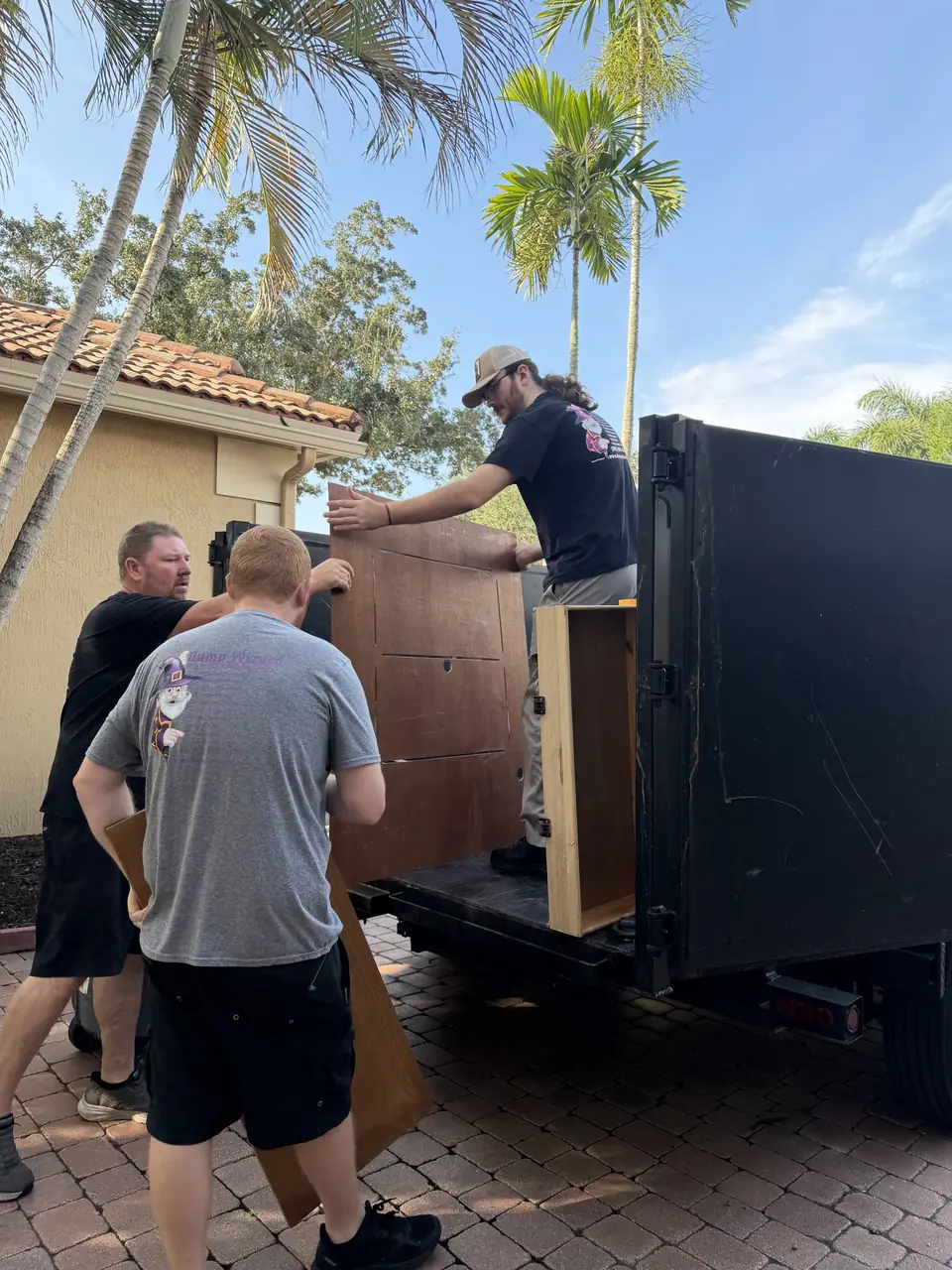 Dump Wizard crew lifting a wooden cabinet onto the trailer during a Parkland cleanout