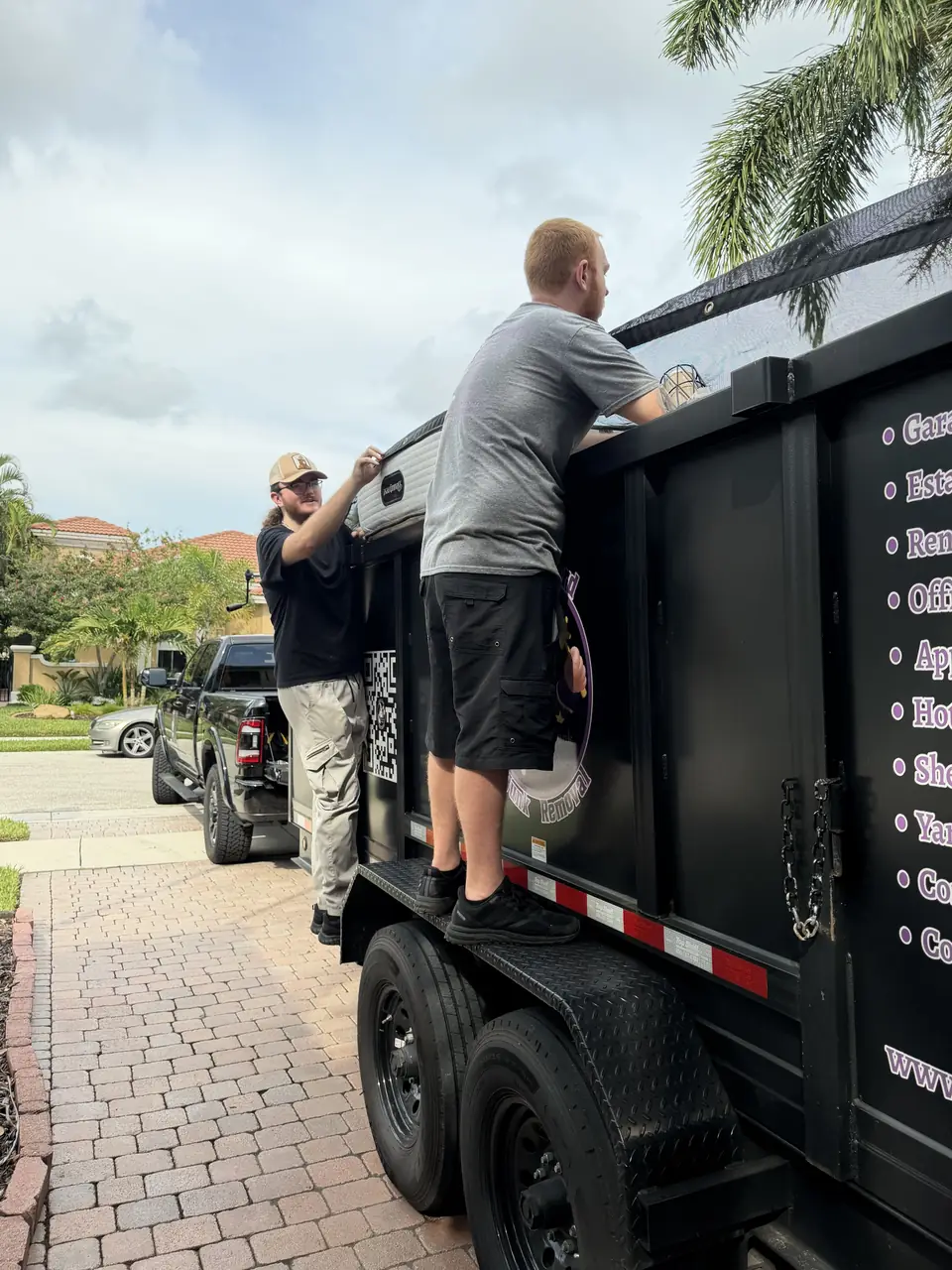 Two Dump Wizard crew members tarping a full load on the wrapped trailer in a Parkland driveway
