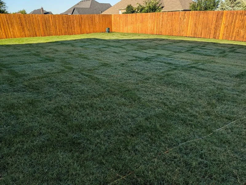 Spacious freshly mowed lawn with visible patterns surrounded by a wooden fence