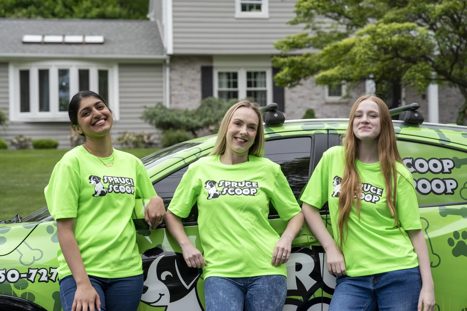 Three Spruce Scoop technicians leaning on the wrapped Spruce Scoop car outside a home