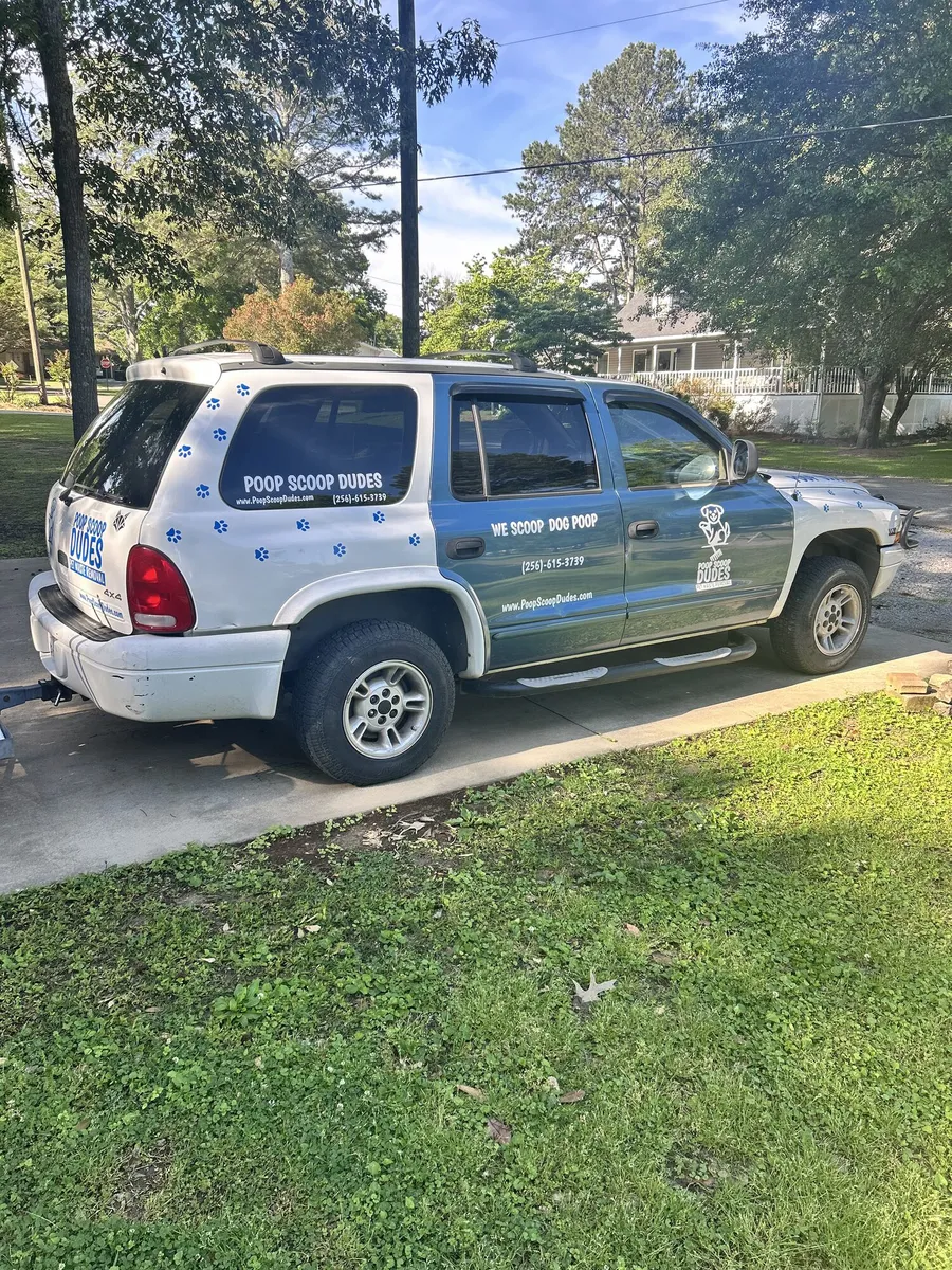 Rear view of the Poop Scoop Dudes branded SUV in a driveway