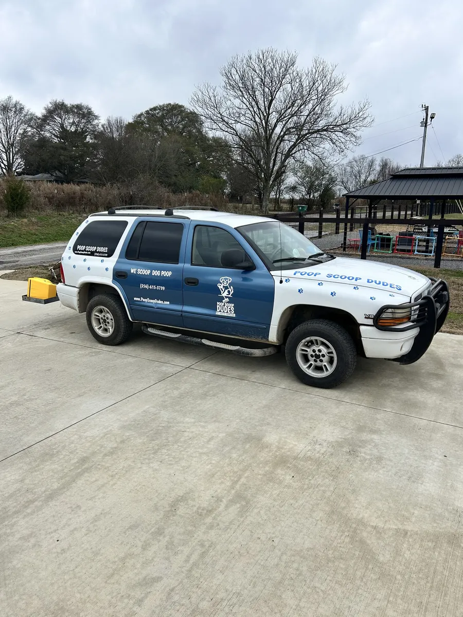 Side view of the Poop Scoop Dudes branded SUV in a driveway