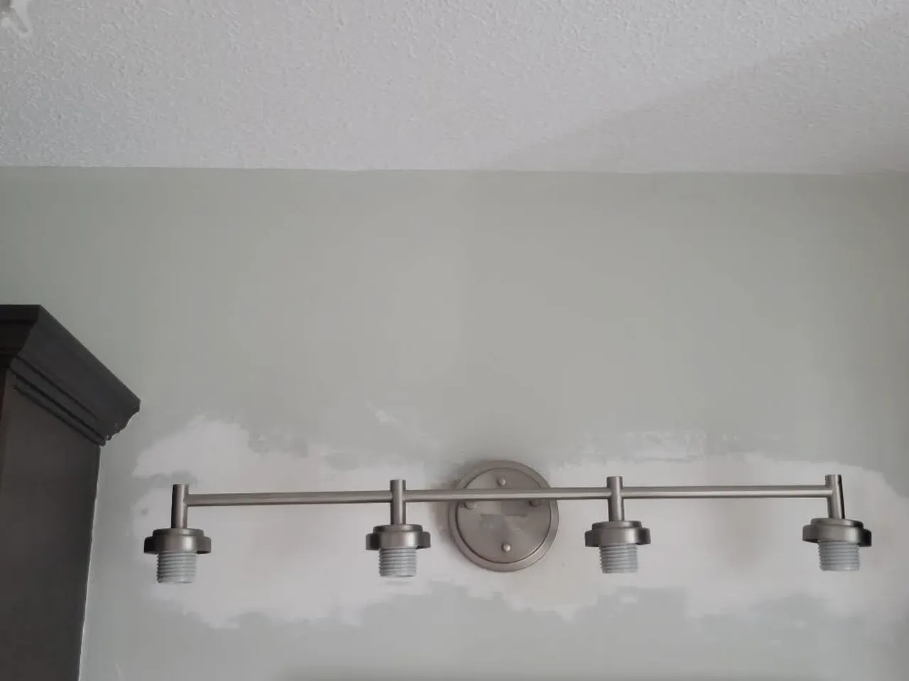 Modern four-socket wall-mounted light fixture installed against a freshly painted wall
