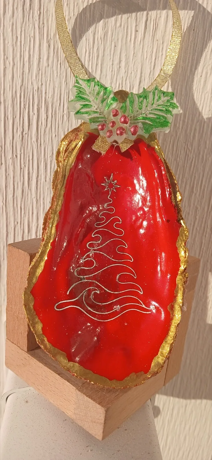 Red and gold oyster shell ornament with an engraved Christmas tree and a holly detail
