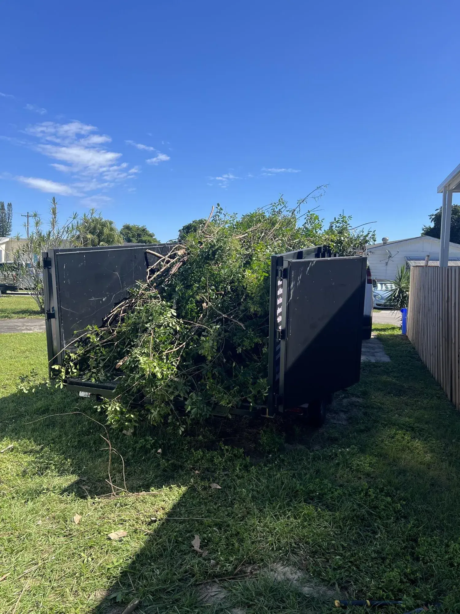 Trailer loaded with branches, palm fronds, and yard debris