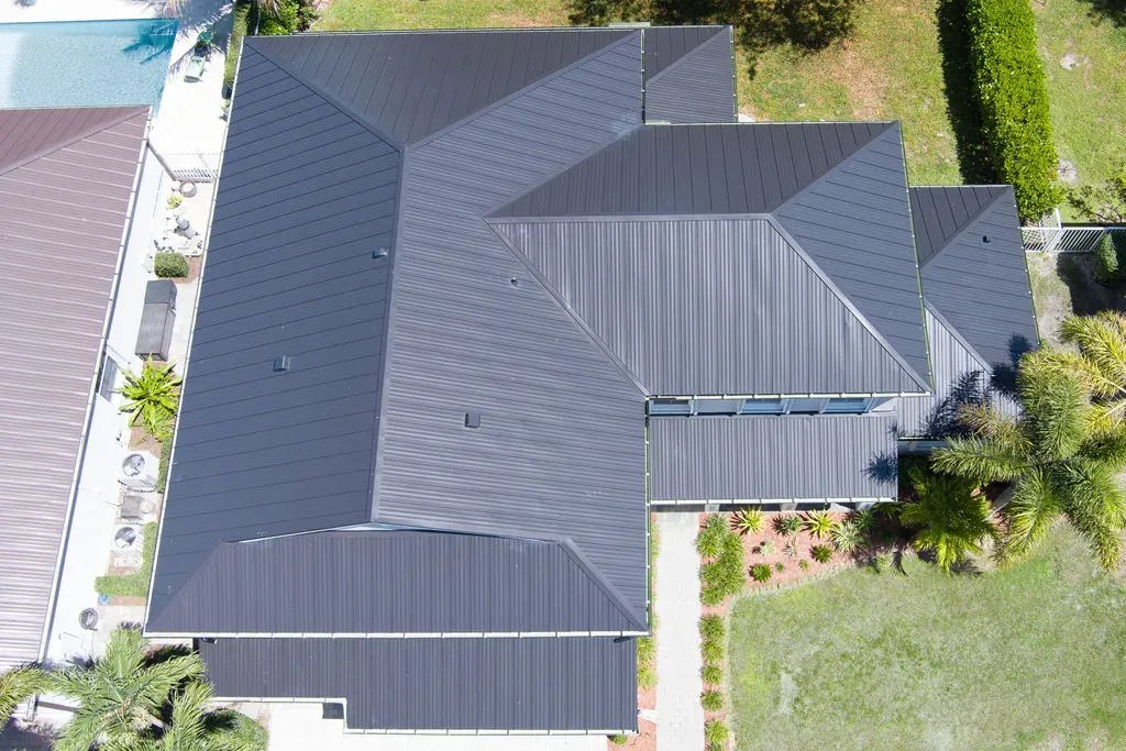 Aerial view of a contemporary home on the Treasure Coast with a sleek black metal roof and pool