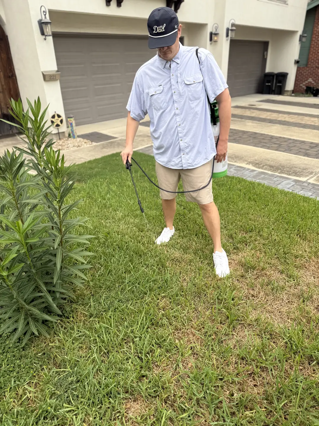 B.P. Foley spraying a lawn with a pump sprayer and wand
