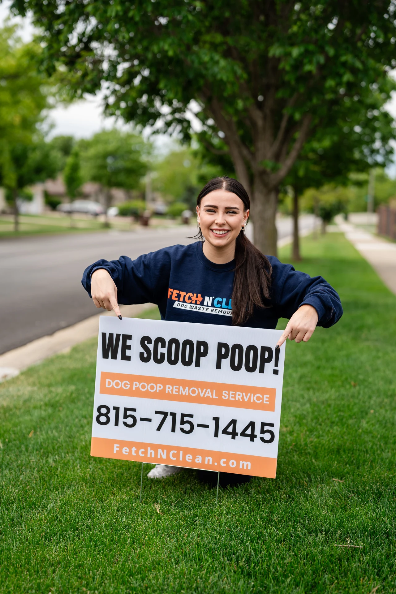 Fetch N Clean team member holding a sign with the phone number and website.