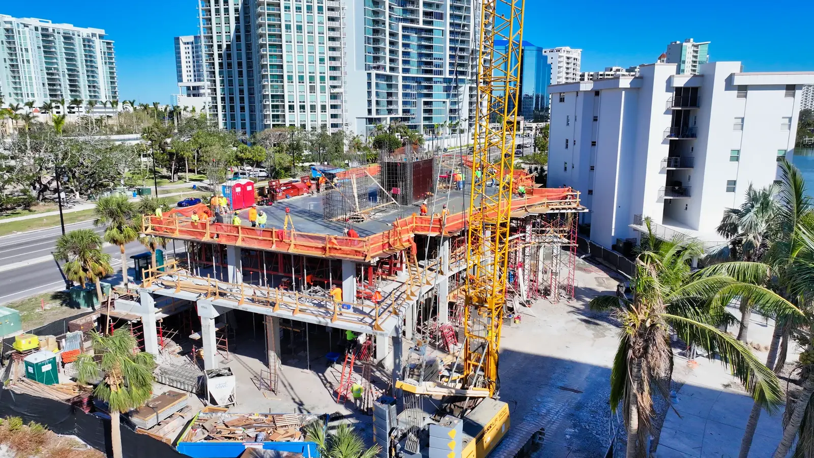 Commercial construction crew working beside scaffolding and a large crane on an active high-rise project.