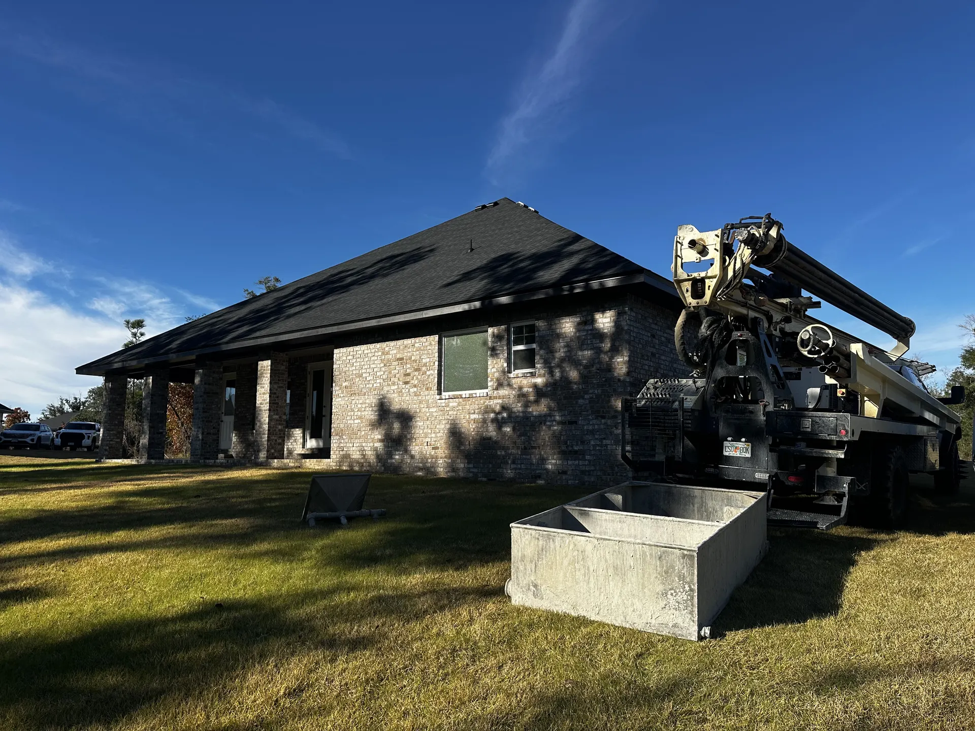 Delivery truck with equipment parked at a brick house preparing to offload a concrete structure