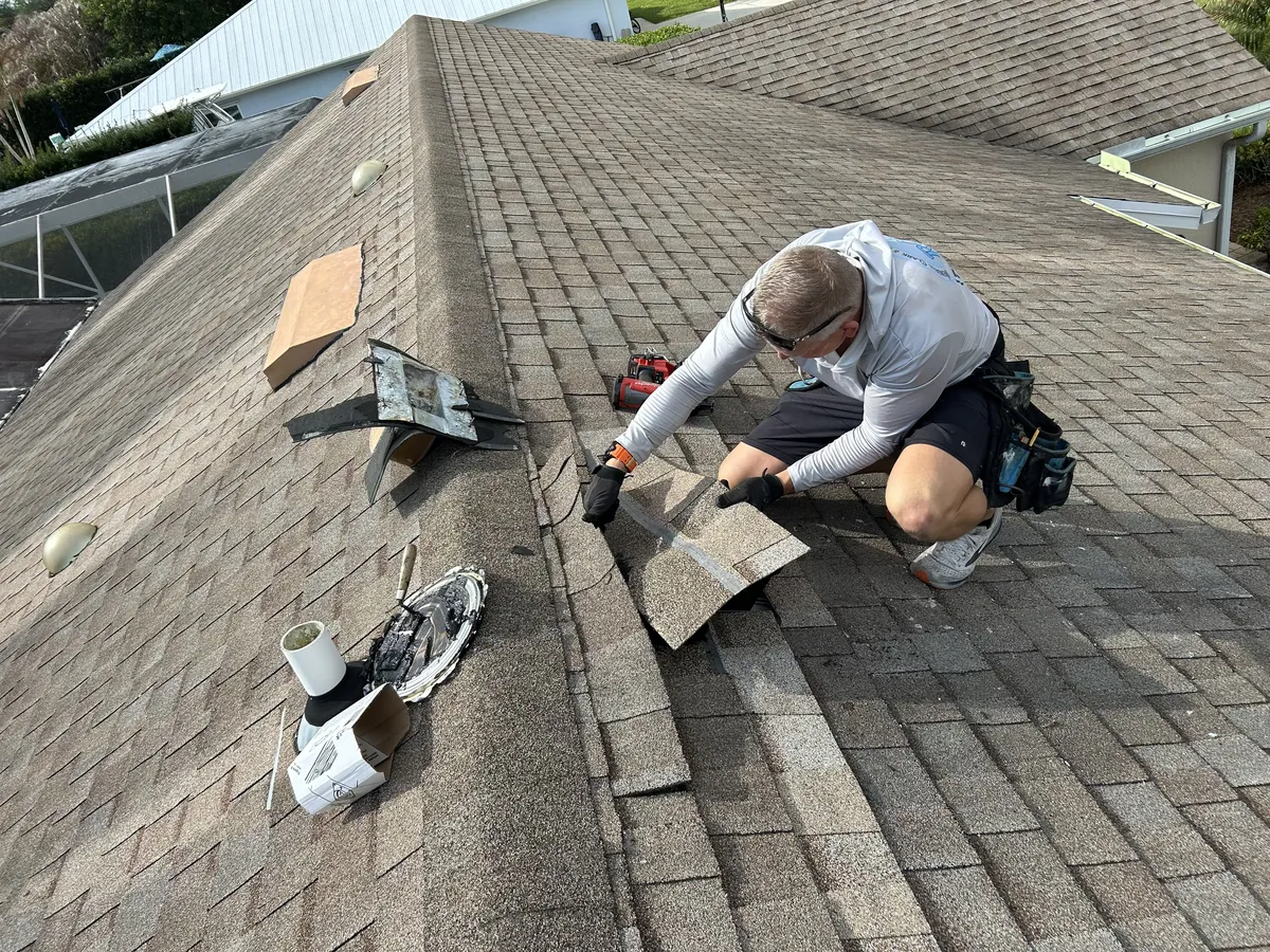 Roofer repairing shingles on a residential roof